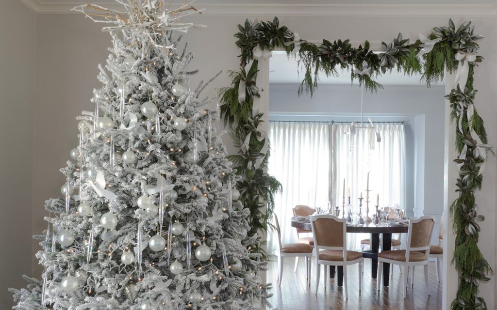 Flocked tree and garlanded doorway in a white living and dining room
