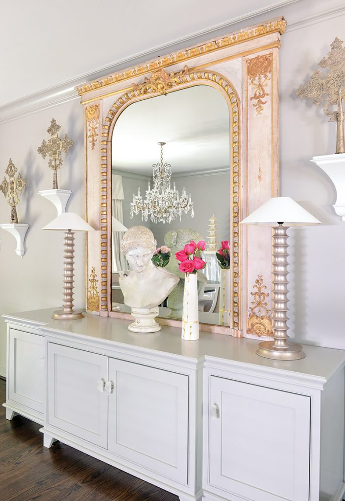 The homeowners’ collection of art and antiques inspired vignettes in each room, such as the one above featuring a centuries-old gilded French mirror and ornate Ethiopian crosses.