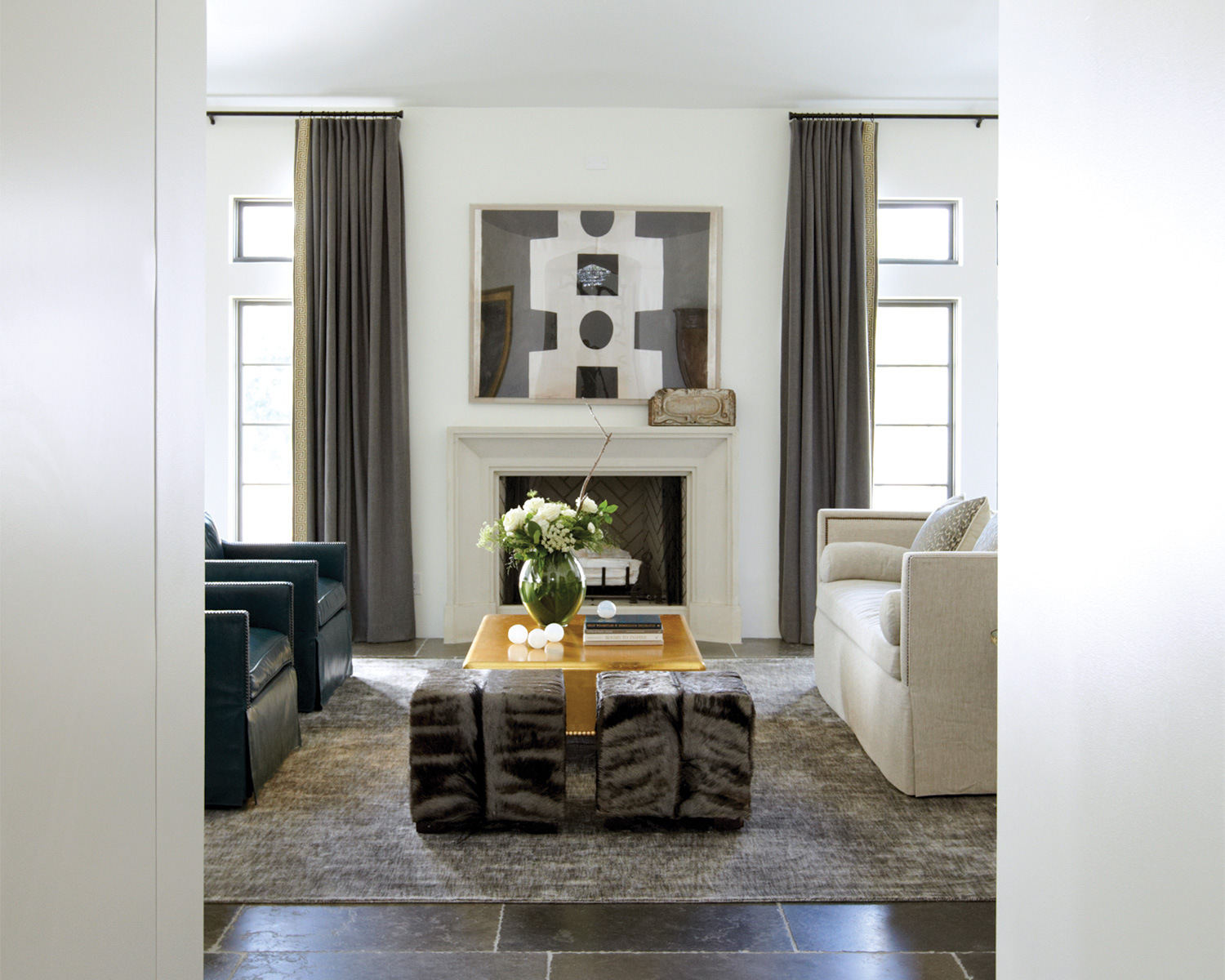 Taupe living room with a tailored fireplace and a hide-covered ottoman