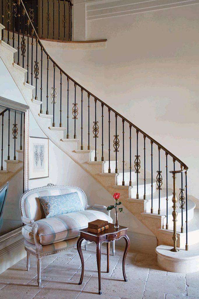 A Louis XVI settee sits in front of a propped mirror in the crook of the entry’s staircase.