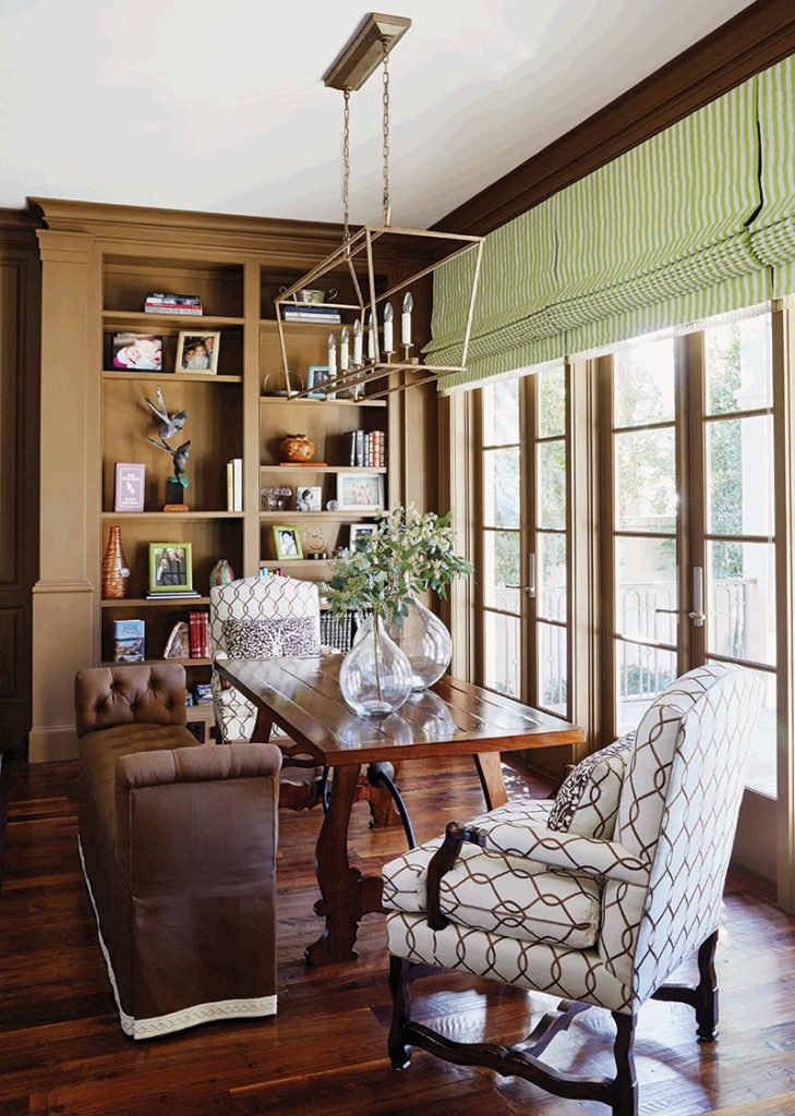 This farm table in the library serves as a spot for paperwork or occasional dining. An upholstered bench covered in Kravet fabric provides versatile seating.