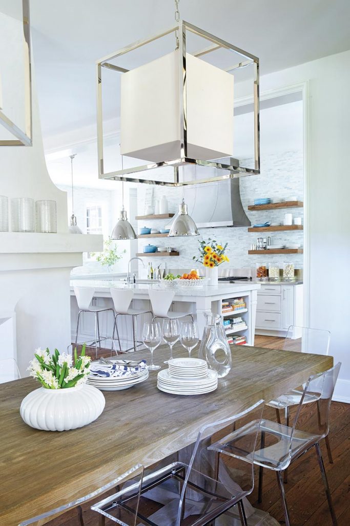 A sturdy farm table pairs with Lucite dining chairs in the breakfast room