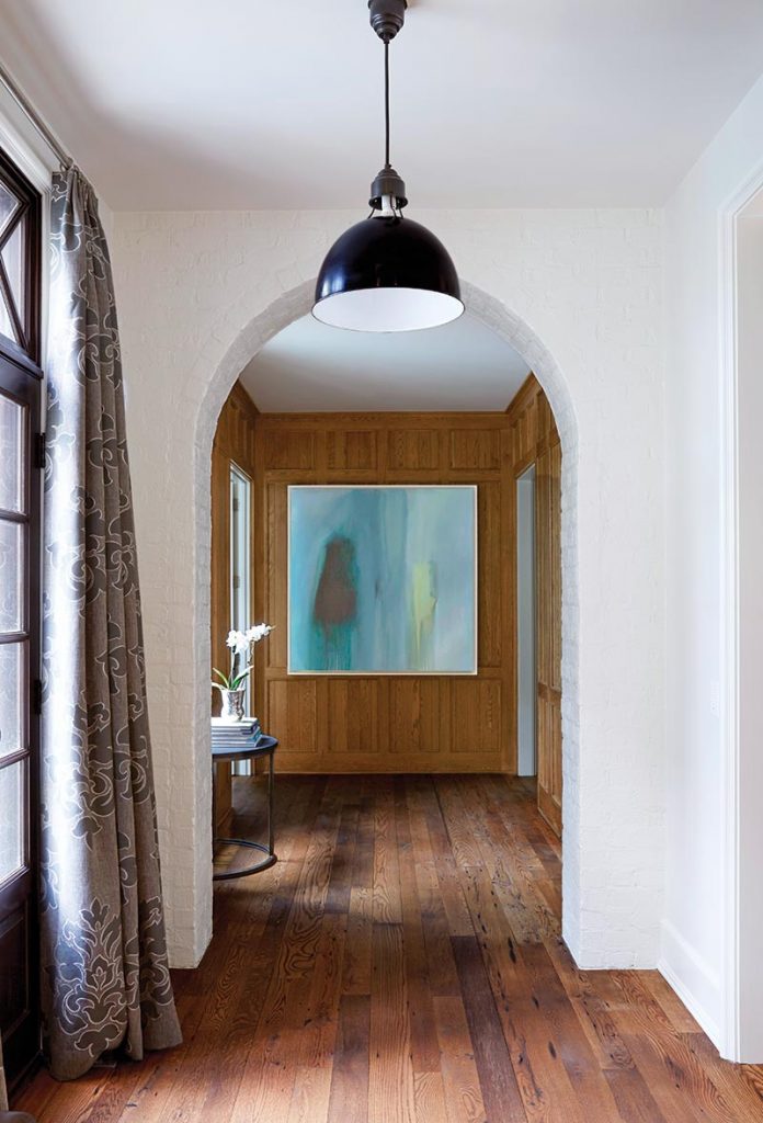 The gallery hallway, a pleasing transition between public and private spaces, displays the homeowners’ artwork.