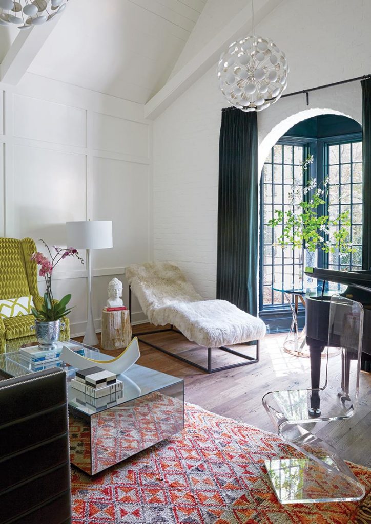 White bedroom with chartreuse chairs and a red patterned rug by an arched doorway