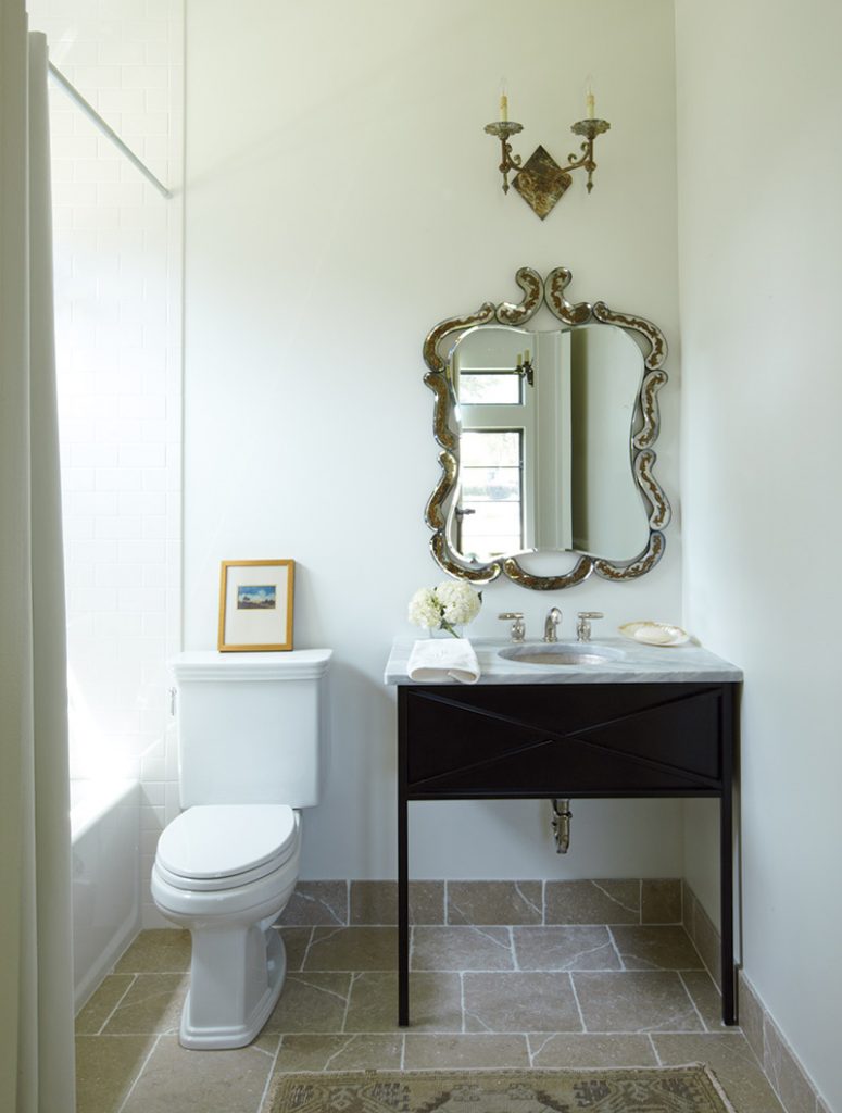 A curvy gold Italian mirror contrasts with a sleek vanity in the guest bath.