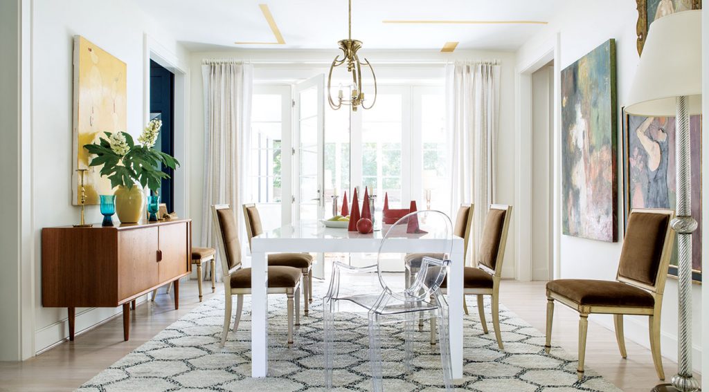 White dining room with a walnut sideboard, patterned rug and modern art