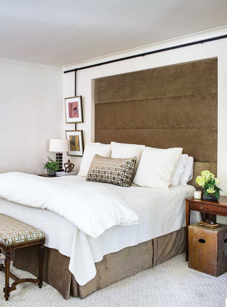 The high headboard in the existing niche left no place for a painting, so an iron bar was fashioned to go over it with side rods to hold a collection of works.