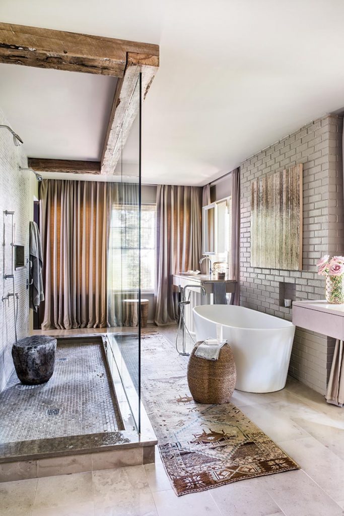 Bath with a freestanding tub, patterned wallpaper and an exposed beam overhead