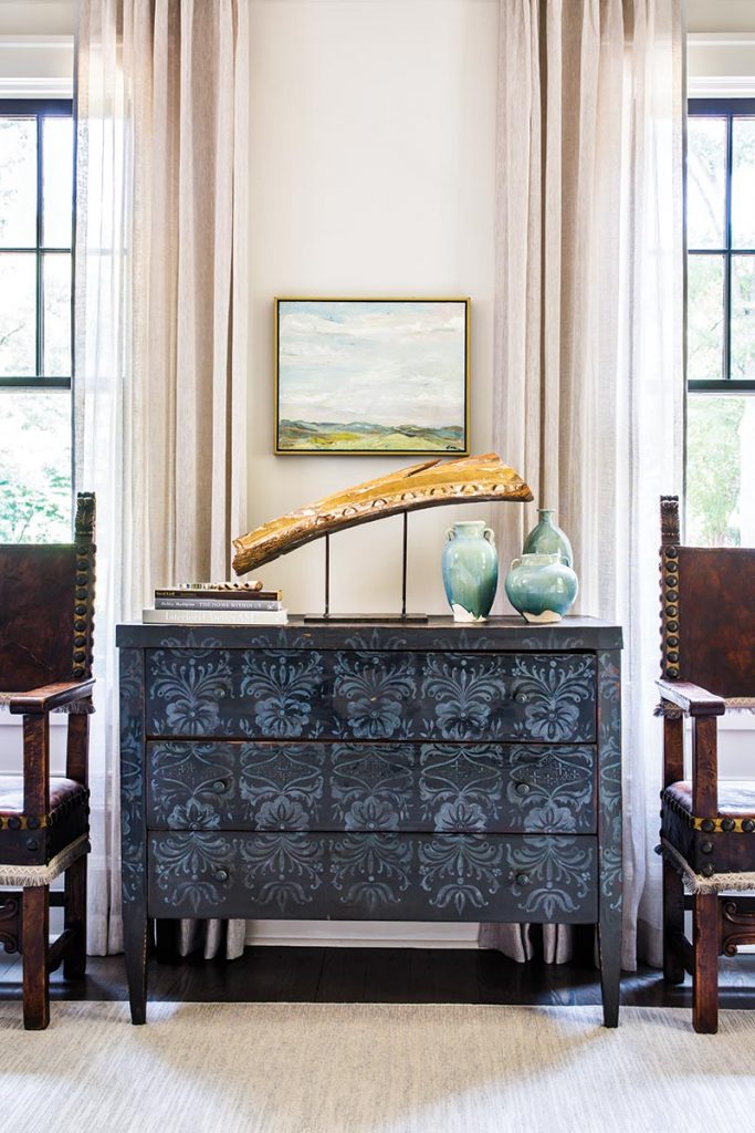 In the living room, Heather Smith created a collected  look with an eclectic mix  of painted furniture, pottery, and a mounted architectural fragment.