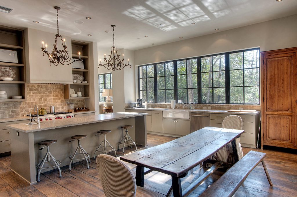 Kitchen with a plaster hood, industrial pendants and a rustic trestle table
