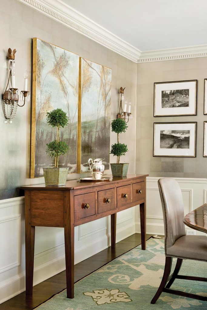 Console table with framed botanicals, topiaries and a pair of sconces