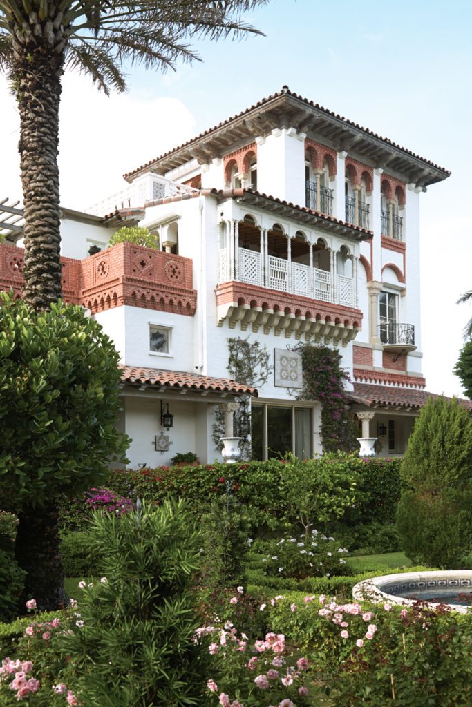 Mediterranean villa with arched loggias above a rose garden and palm