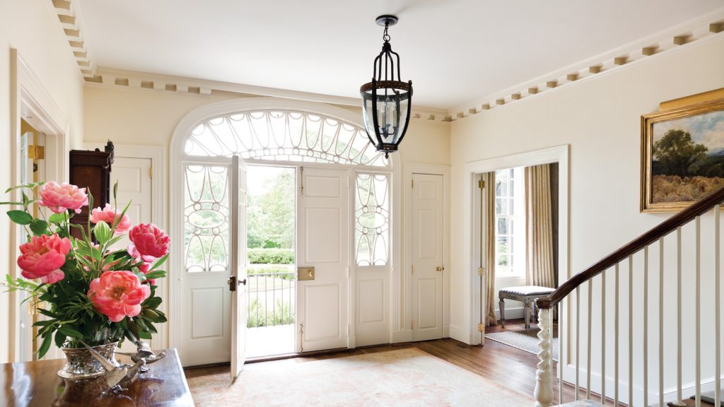 The intricate Palladian transom and leaded sidelights of the entry immediately speak to the elegance permeating the entire interior. Dentil molding in an exaggerated scale accents the perimeter of the room with style that’s simultaneously classic and playful, and the subtle swirl adorning the stair risers shows superb attention to detail.