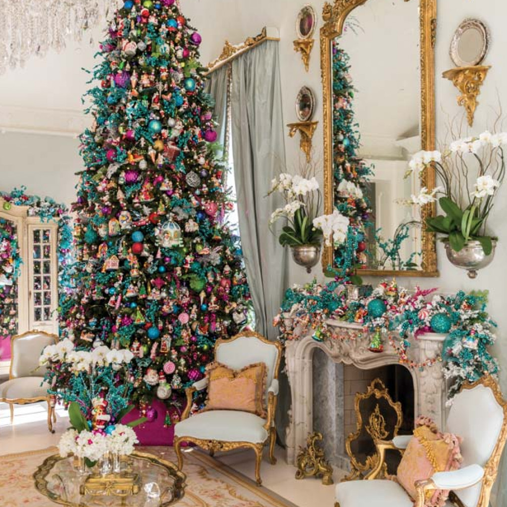 Christmas tree trimmed in jewel tones beside a mantel with white orchids