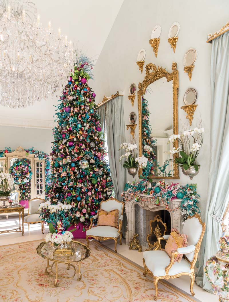 Christmas tree trimmed in jewel tones beside a mantel with white orchids