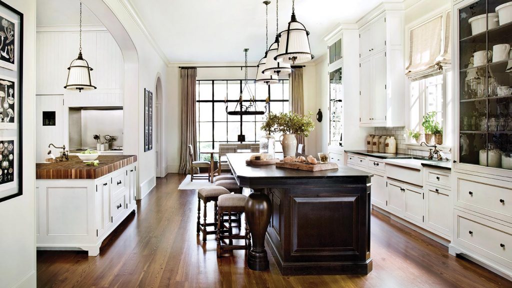 Long white kitchen with a dark island, industrial pendants and open shelving