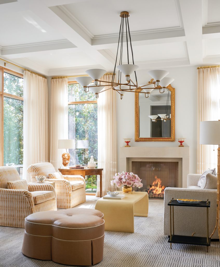 Living room with cream chairs, a stone mantel and bay window