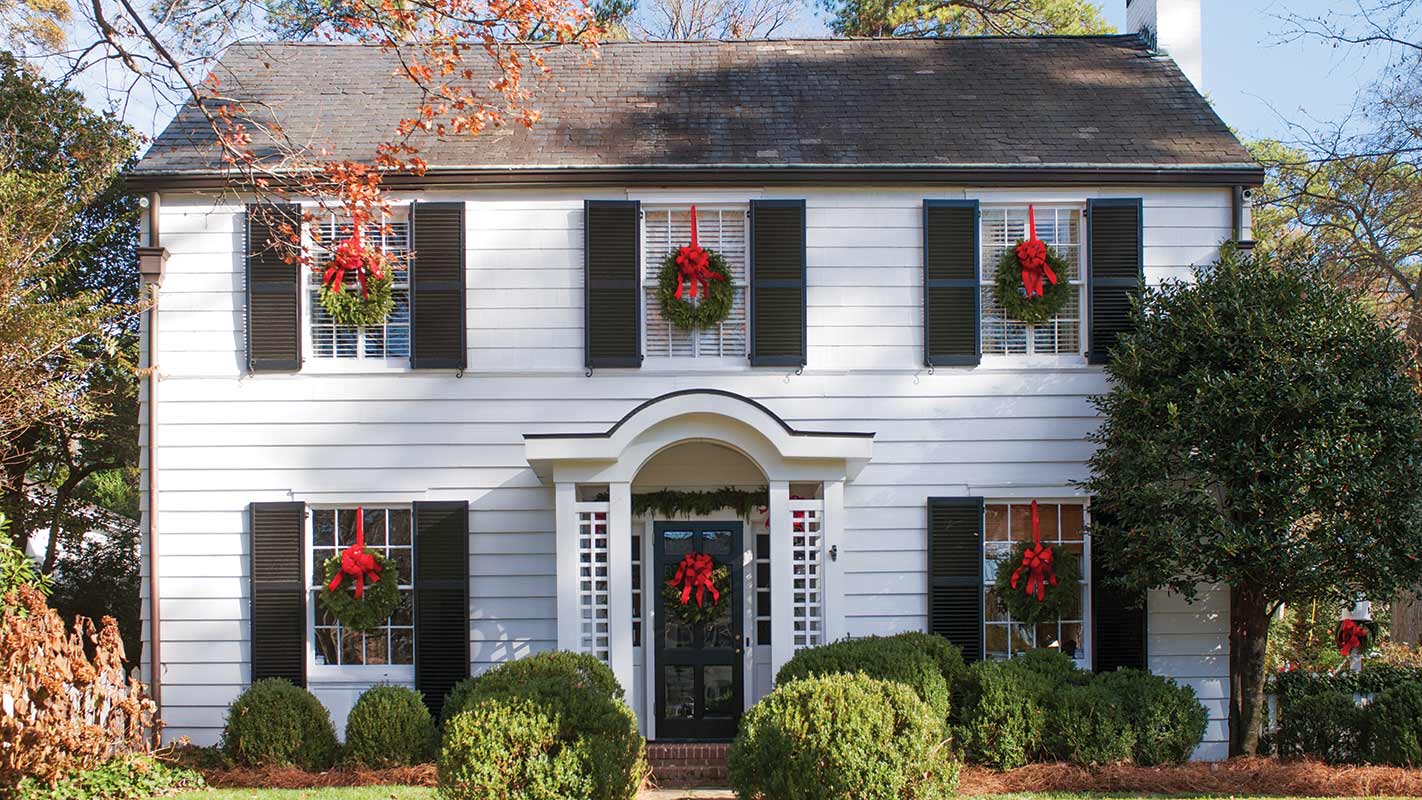 White clapboard Colonial dressed for Christmas with wreaths at every window