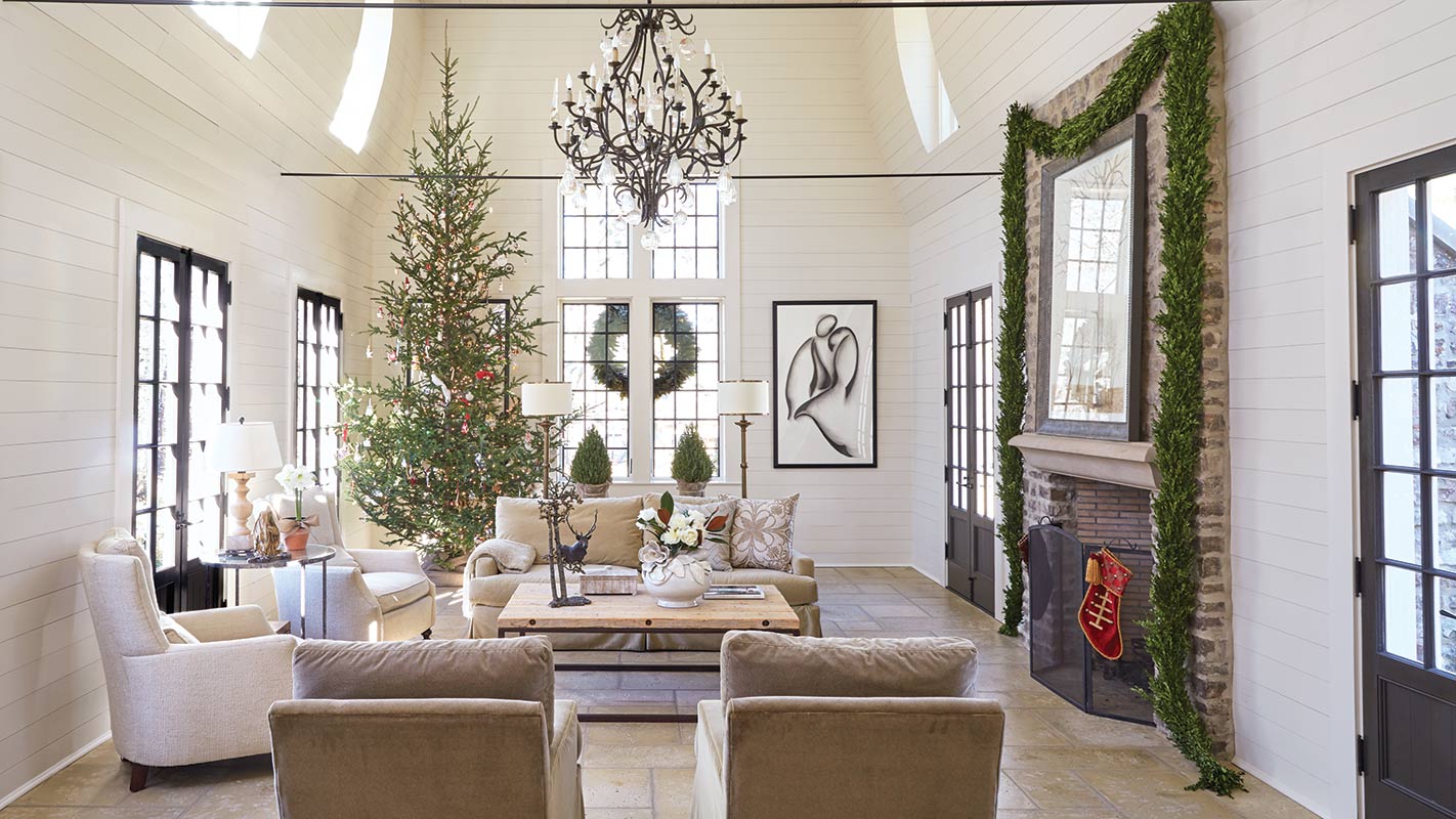 White living room with garland-draped doorways and a slim Christmas tree