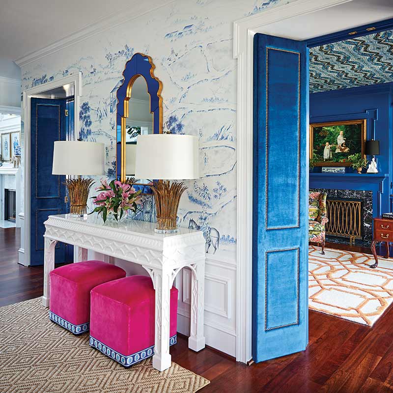 front entry with blue-and-white wallpaper and pink upholstered cubes