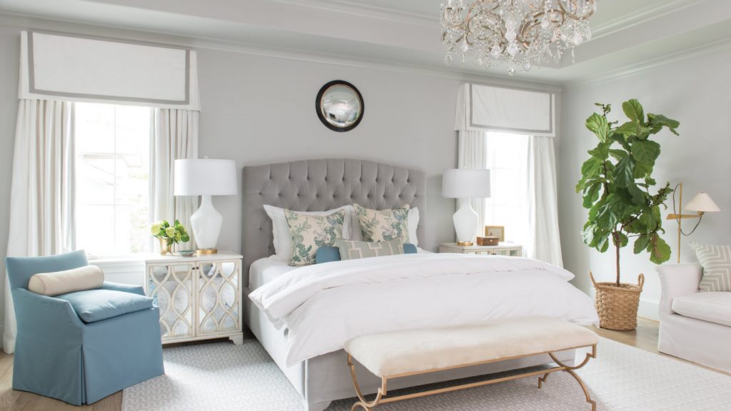 Grey bedroom with a tufted headboard, blue chairs and an upholstered bench