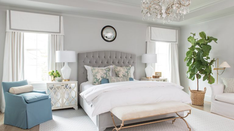 Grey bedroom with a tufted headboard, blue chairs and an upholstered bench