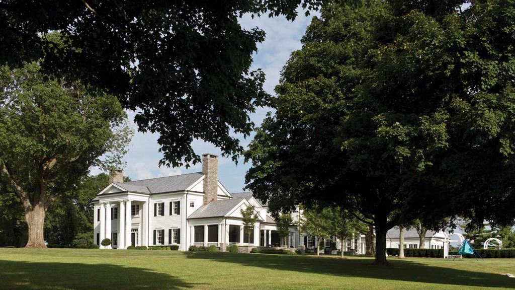 White Greek Revival house across a lawn shaded by huge live oaks
