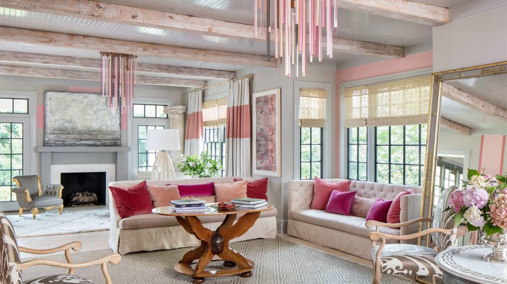 Sunroom with pink striped curtains, magenta pillows and a stone fireplace