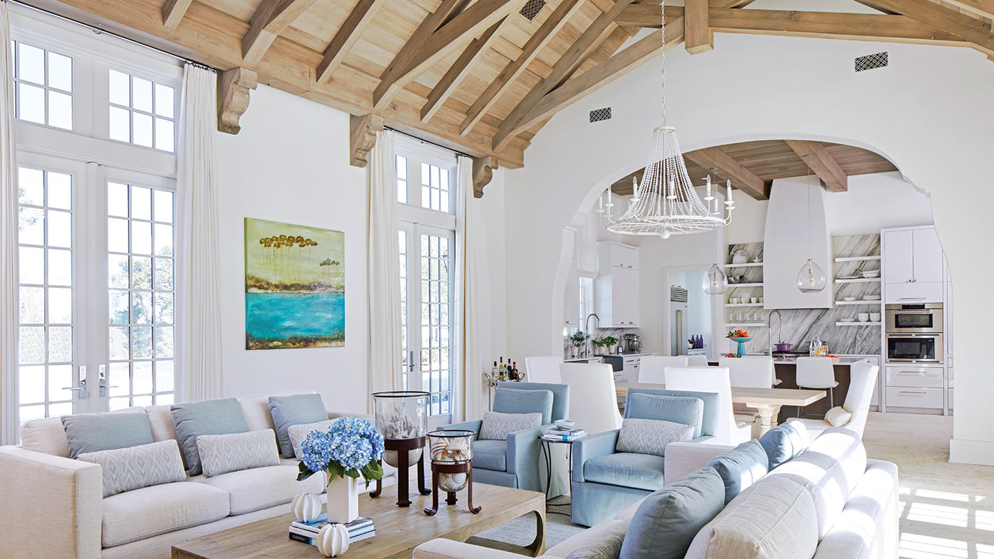 Living room with a timber vaulted ceiling, white sofas and blue hydrangeas