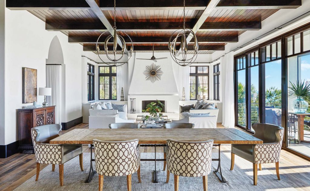 Dining room with a plaster fireplace, patterned chairs and iron chandeliers