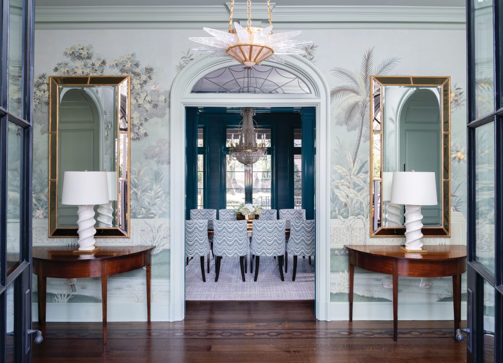 Blue dining room seen between demilune consoles with white lamps