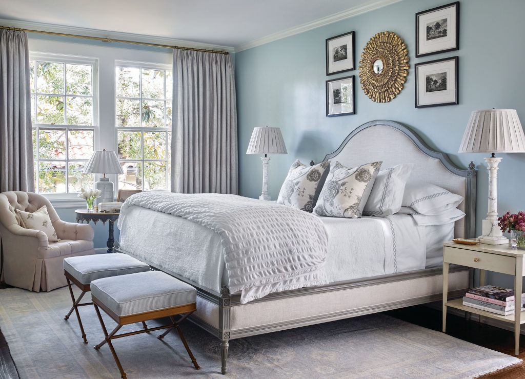 Bedroom with an arched upholstered headboard and a gallery of framed art