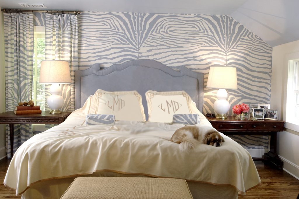 Bedroom with a scalloped headboard, animal-print wallpaper and a dog on the bed