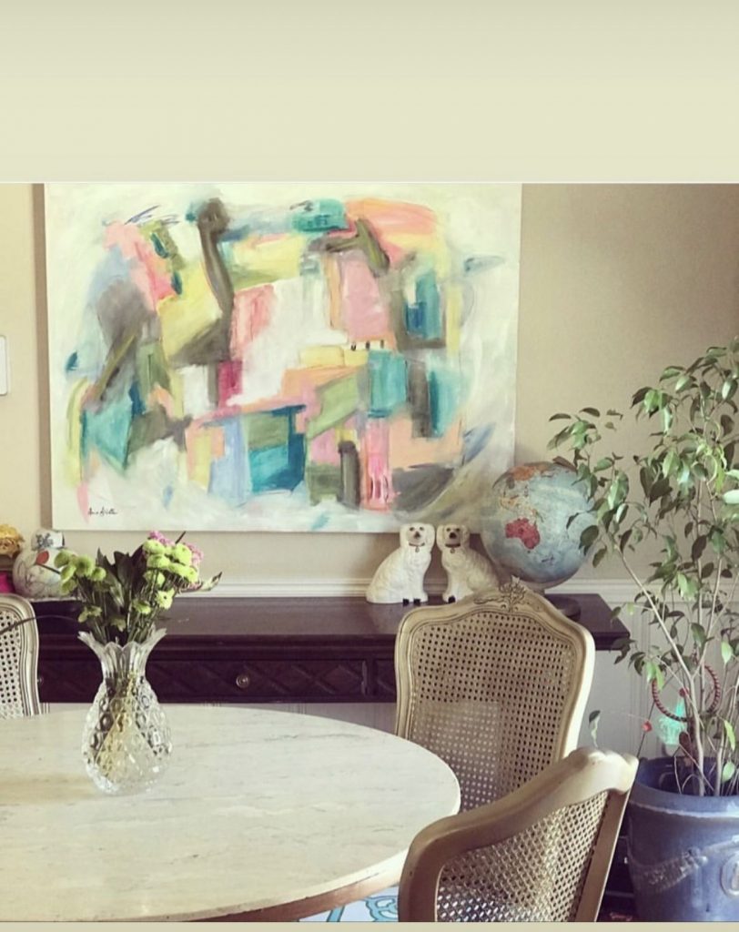 Bright abstract canvas above a round table with a woven chair