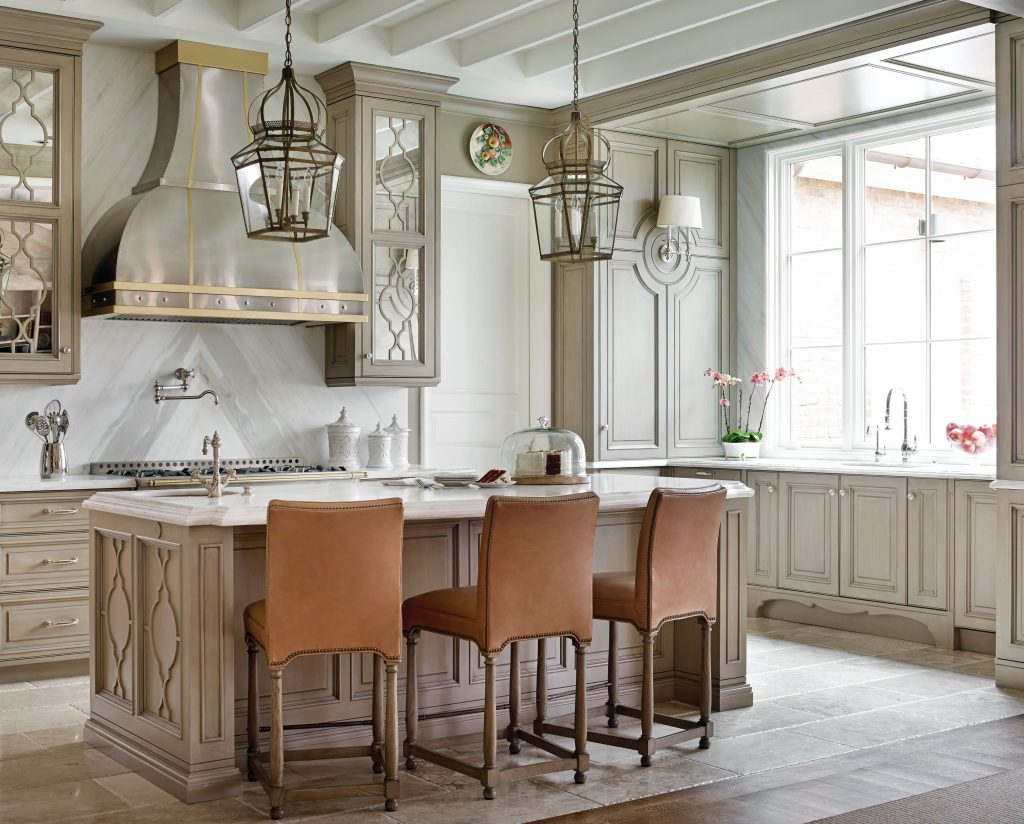 Cream kitchen with a plaster hood, lanterns and leather counter stools