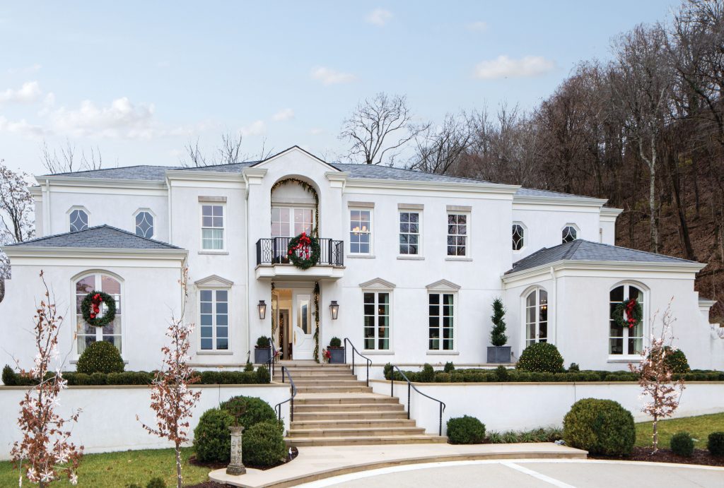 White house with a portico, wreaths in every window and clipped topiary