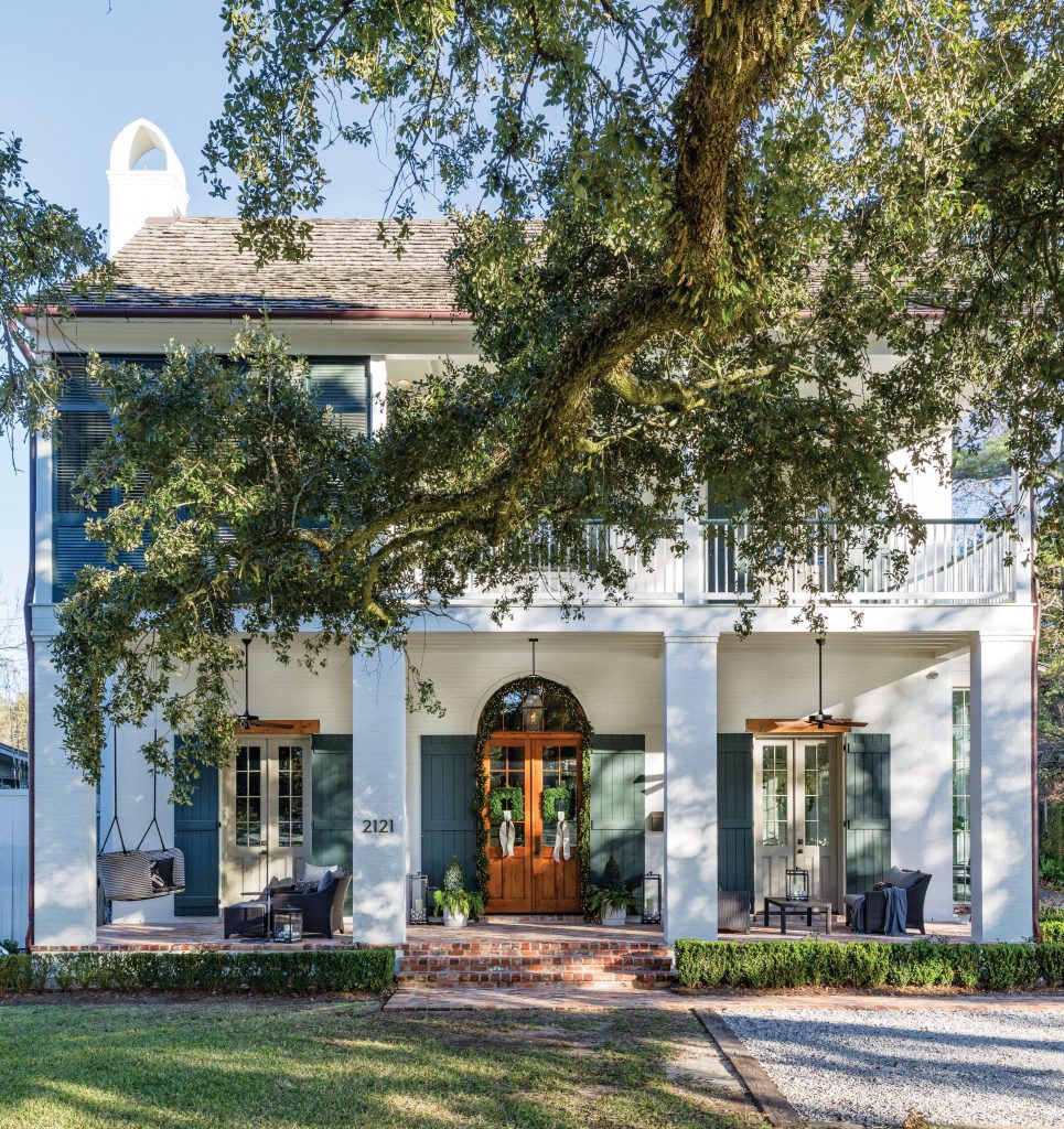 White house with columned porches beneath a spreading live oak