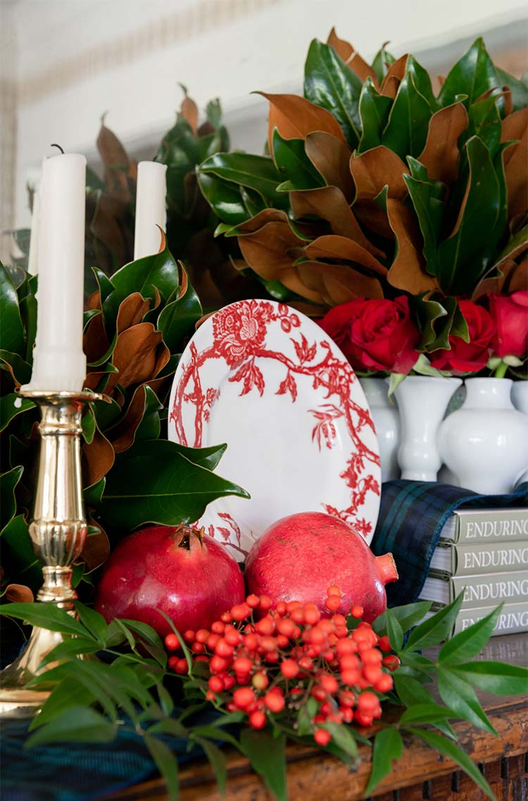 Centrepiece of magnolia leaves, pomegranates and berries with white candles