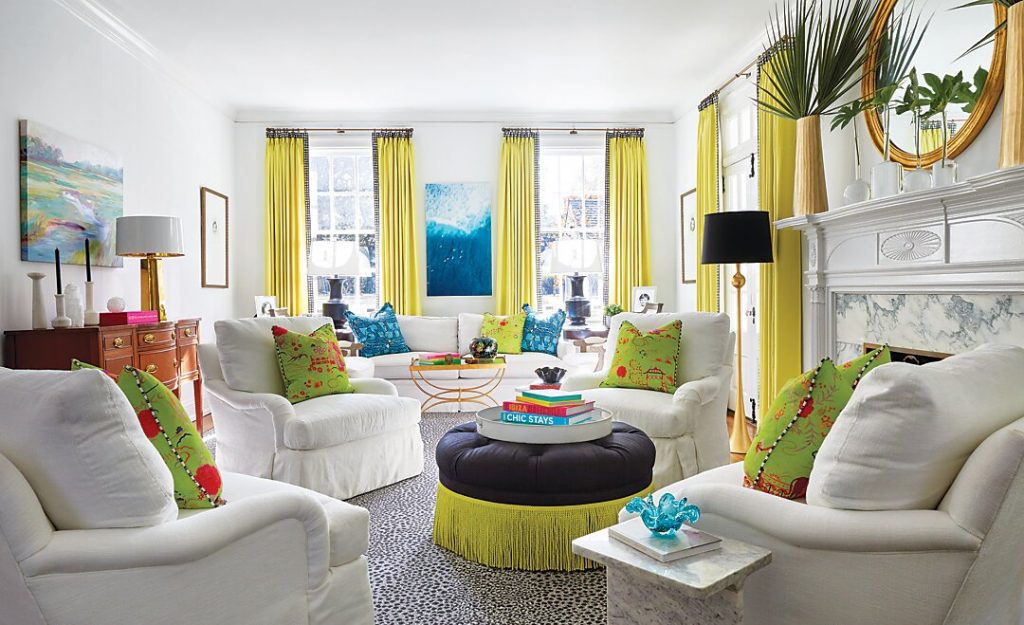 Living room with chartreuse curtains, a navy ottoman and coastal art