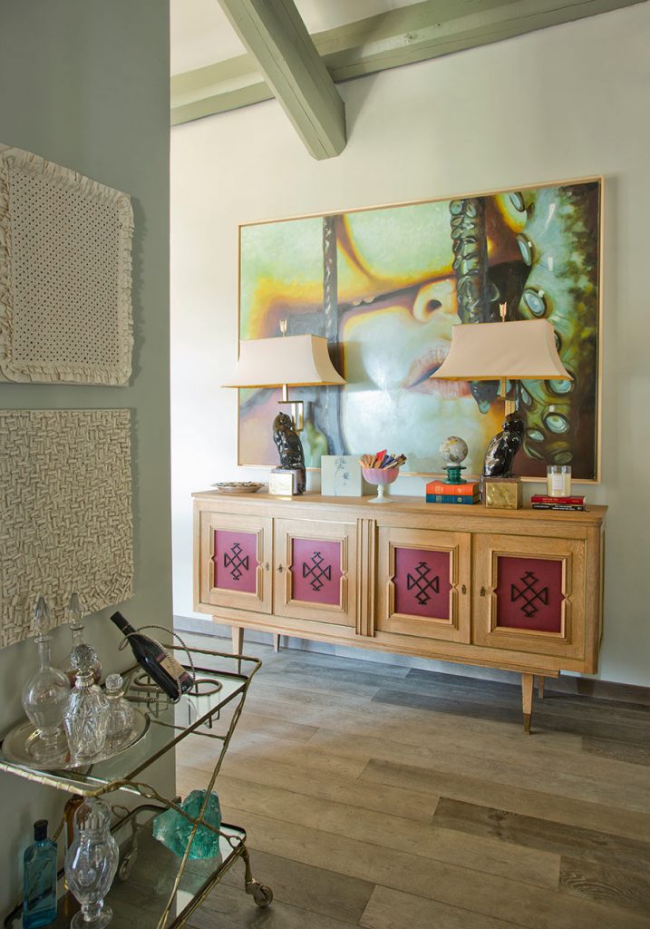 Painted sideboard with a bright canvas above and a glass bar cart