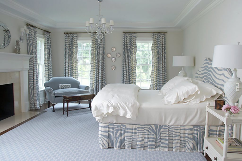 Bedroom with a striped bed skirt, blue curtains and a settee
