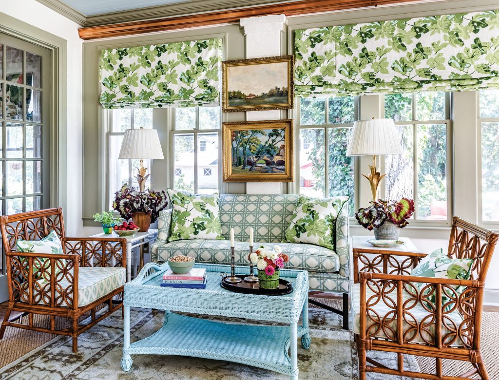 Sunroom with rattan chairs, green leaf-print shades and an aqua table
