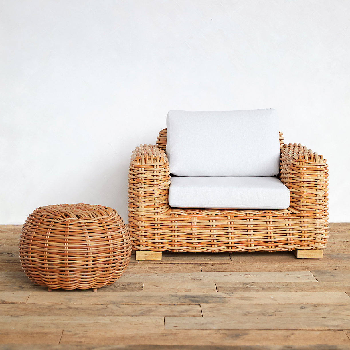 Wicker lounge chair with white cushions beside a woven basket