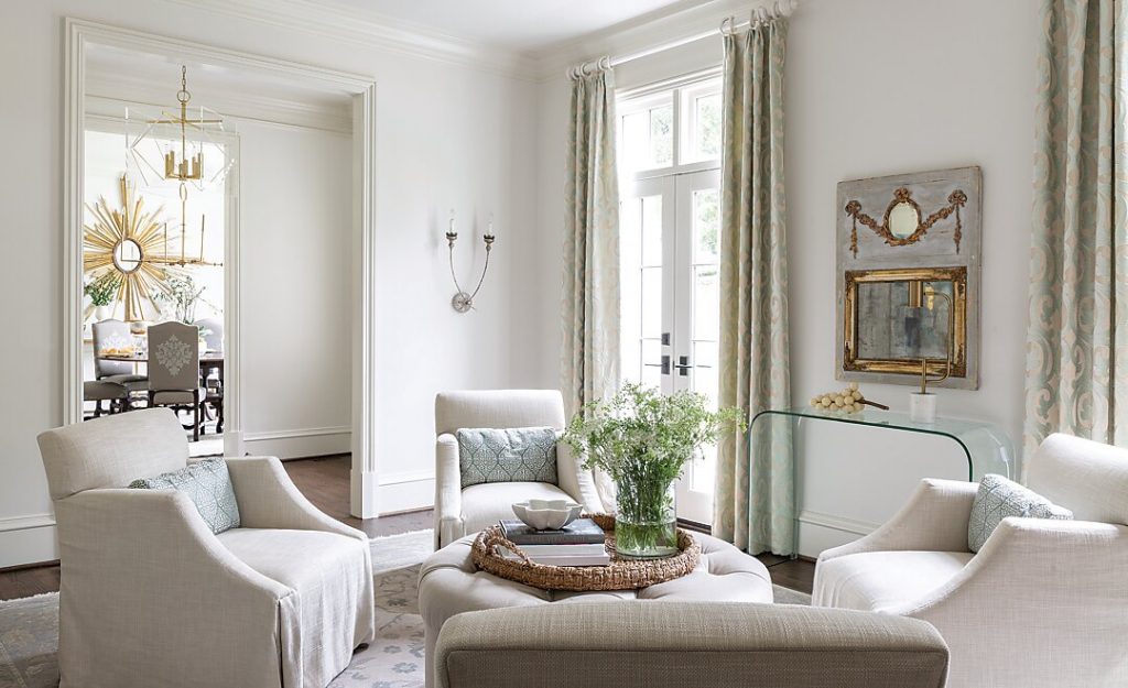Pale living room with slipcovered seating and tall curtained windows