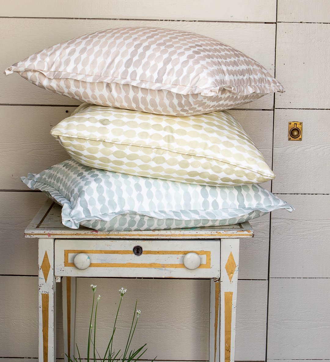 Stack of gingham and striped pillows on a painted bench