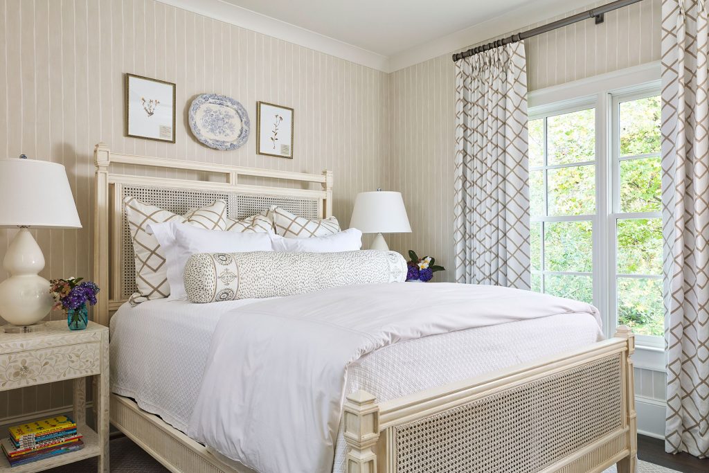 Bedroom with a cane bed, white linens and patterned curtains