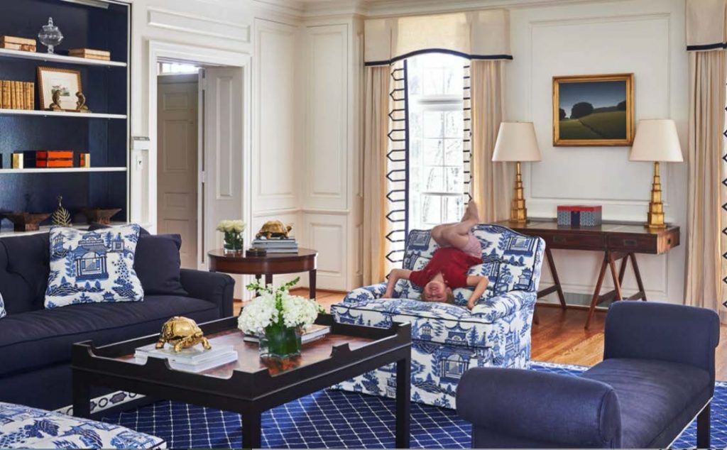 Navy living room with a toile chair, patterned rug and built-in shelves