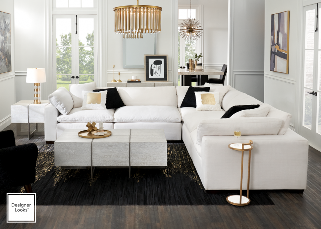 Modern living room with white sectionals, brass tables and a linear chandelier