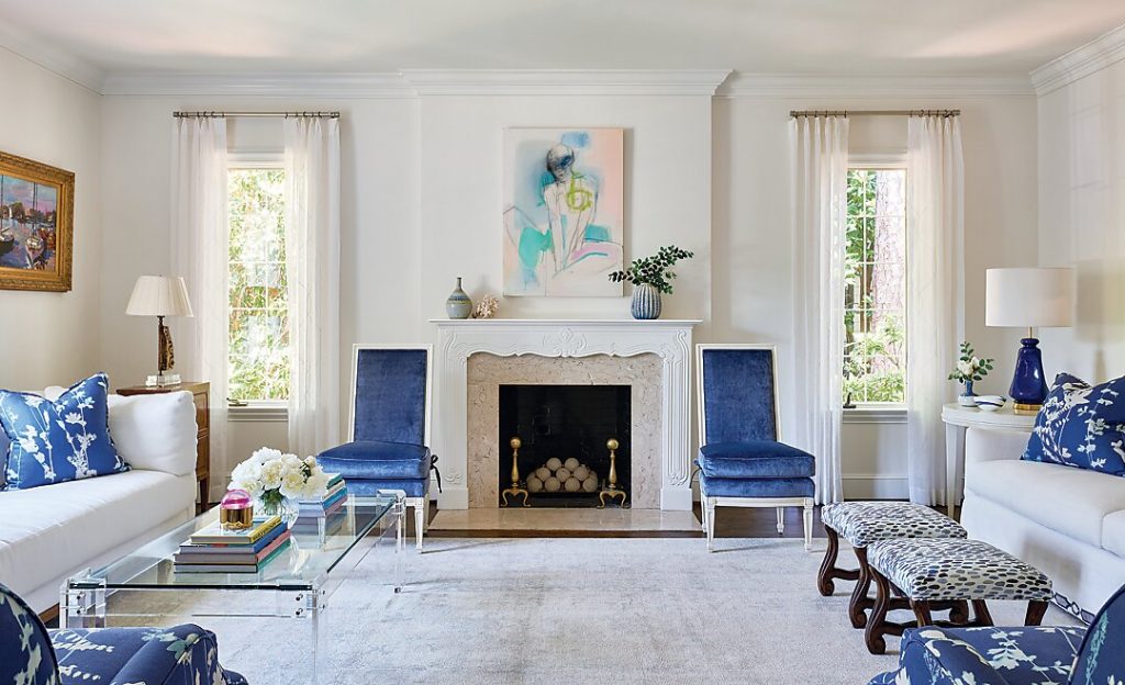 In the living room, a Lucite coffee table and sleek armless chairs are juxtaposed by 18th-century French commodes and Os du Mouton stools. The mix of furniture styles keeps the antiques feeling fresh.