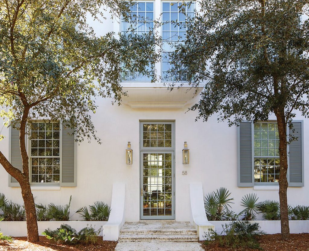 White stucco house entry framed by two clipped trees